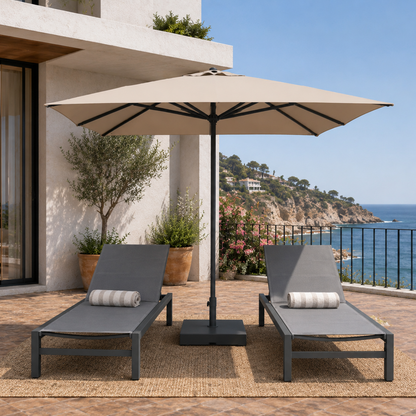 Outdoor patio with two lounge chairs and a large umbrella overlooking a scenic ocean view.