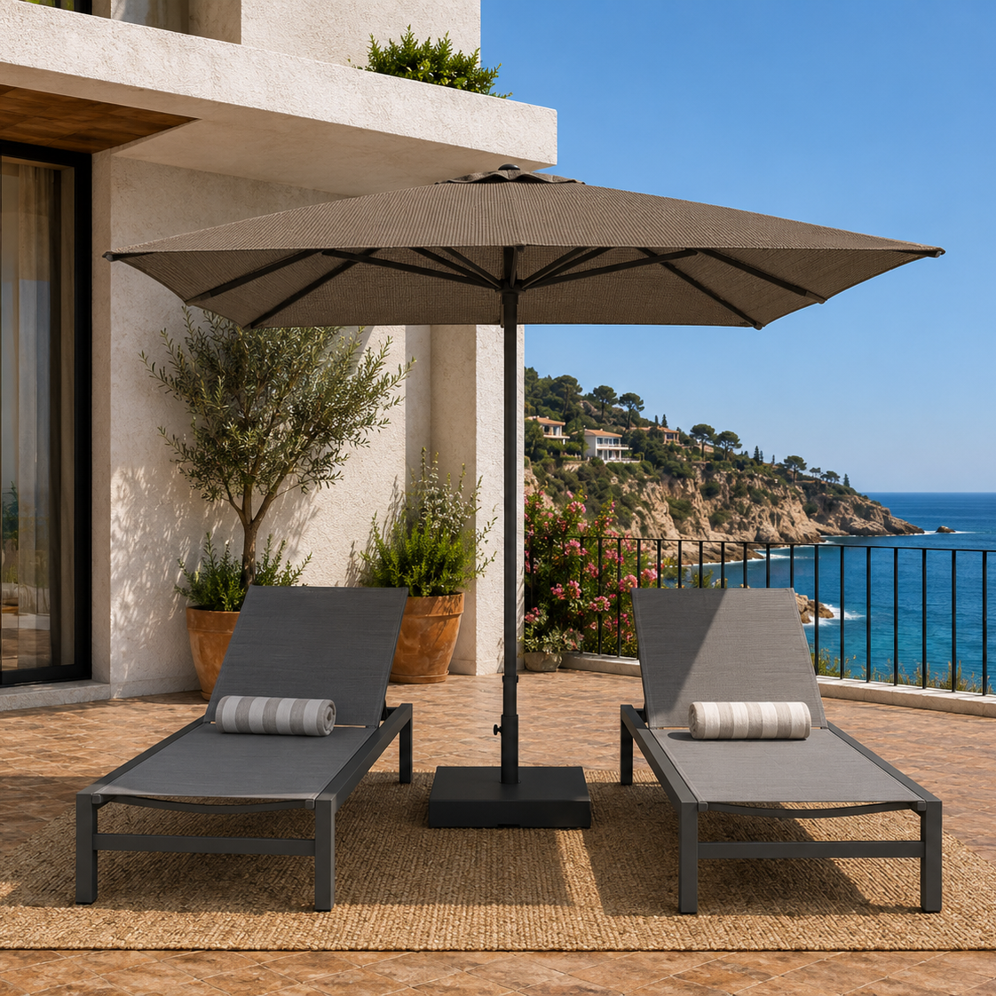 Two lounge chairs under a large patio umbrella on a deck with ocean view.