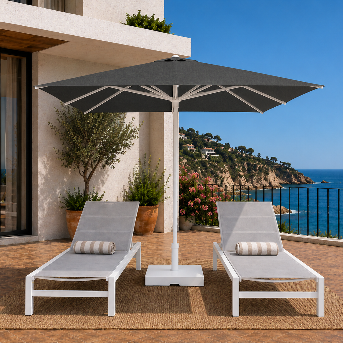 Two lounge chairs under a large umbrella on a patio with ocean view