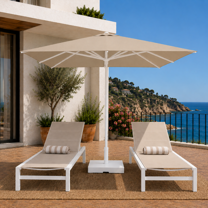 Two lounge chairs under a large beige umbrella on a patio with ocean view