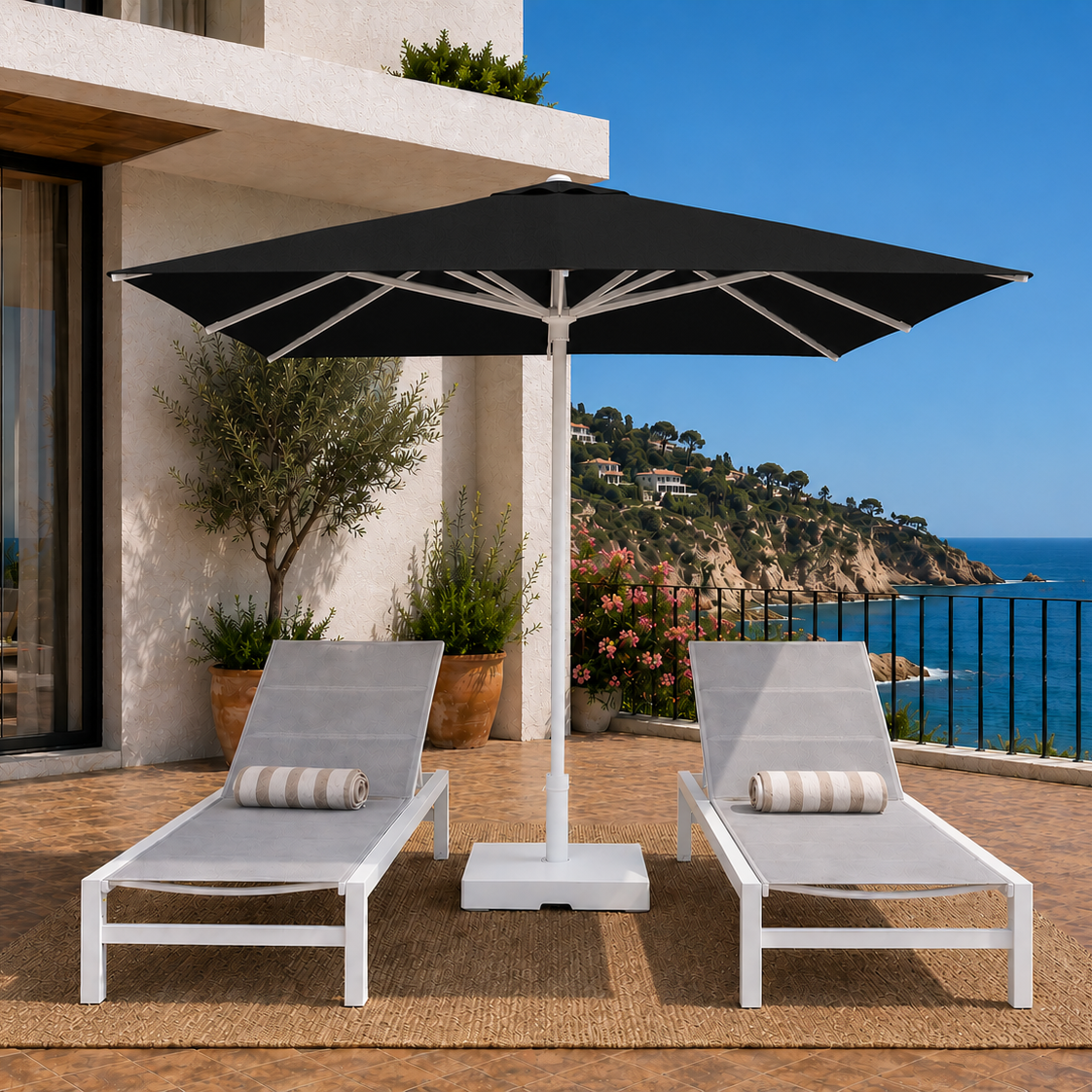 Two lounge chairs under a large black umbrella on a deck with ocean view