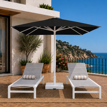 Two lounge chairs under a large black umbrella on a deck with ocean view