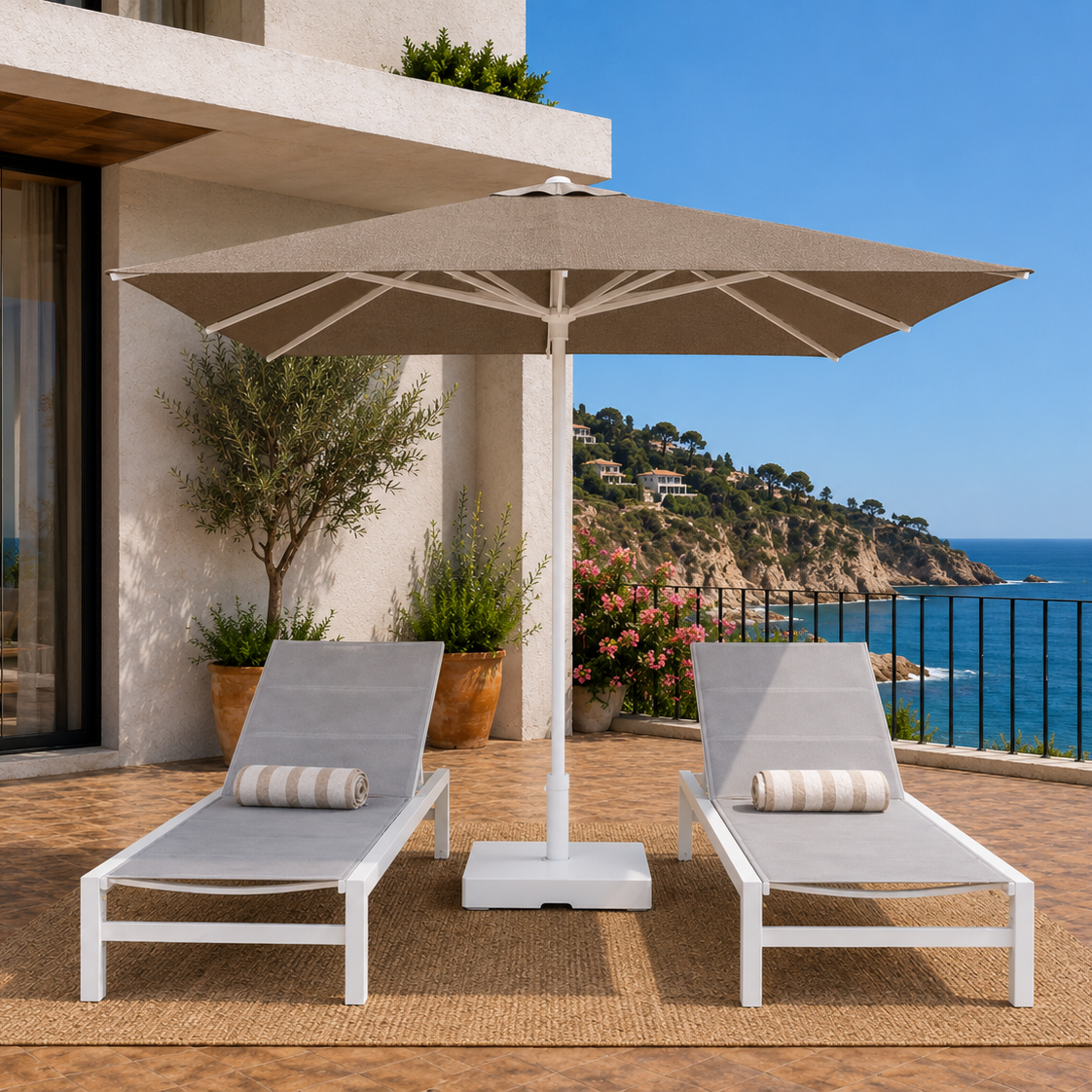 Two lounge chairs with an umbrella on a deck overlooking the ocean.
