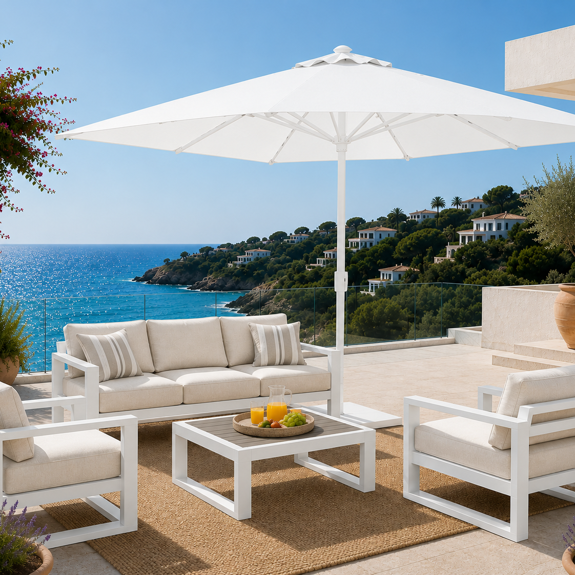 Outdoor patio set with white furniture and umbrella overlooking the ocean.