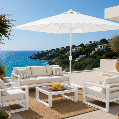 Outdoor patio set with white furniture and umbrella overlooking the ocean.